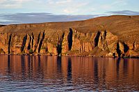 [#526] Klippa, sandsten, sandstensklippa, röd, kvällssol, vatten, fjord, spegling, Båtsfjorden